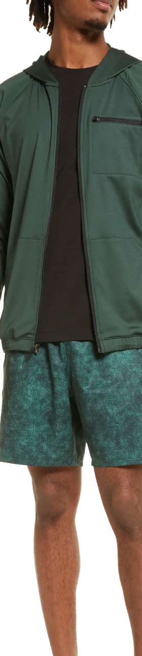 A man standing in a green Zella by Nordstrom  jacket and shorts