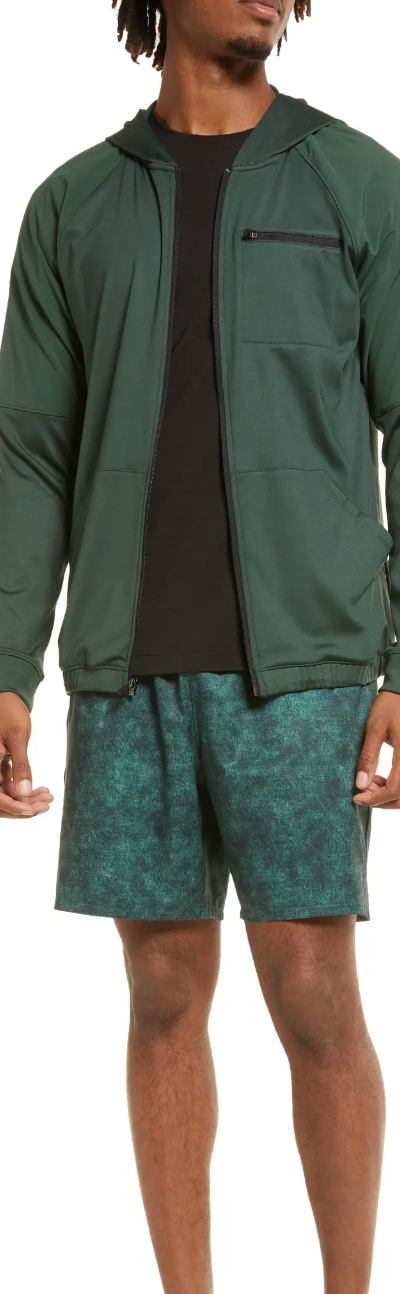 A man standing in a green Zella by Nordstrom  jacket and shorts