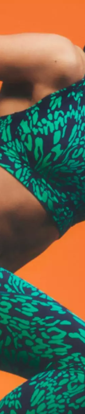A woman mid-sprint wearing a colorful green Sweaty Betty athletic spandex