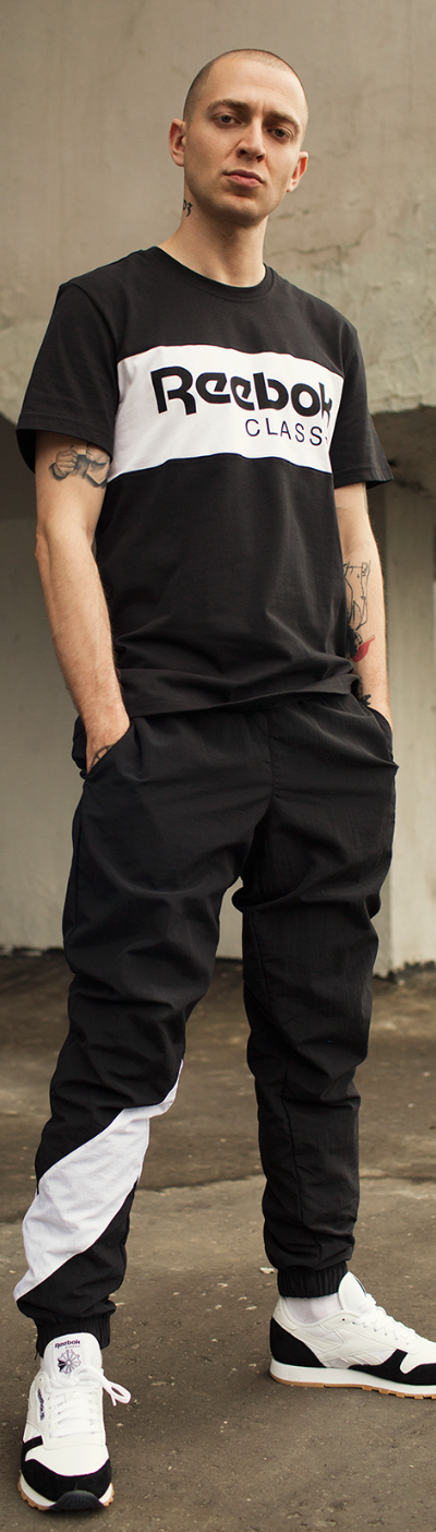 A man standing wearing a black and white Reebok Classics outfit with matching sneakers