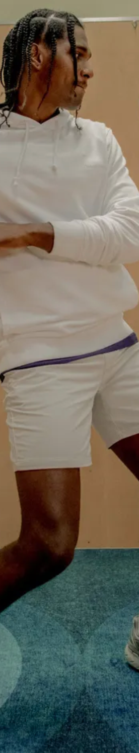 A man wearing a Outdoor Voices white hoodie, short shorts and matching socks