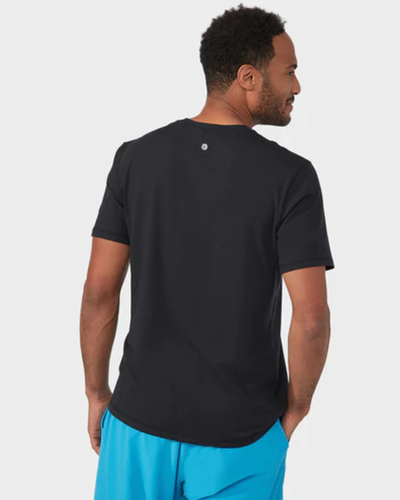 A man wearing a Manduka athletic outfit with a black shirt and bright blue pants