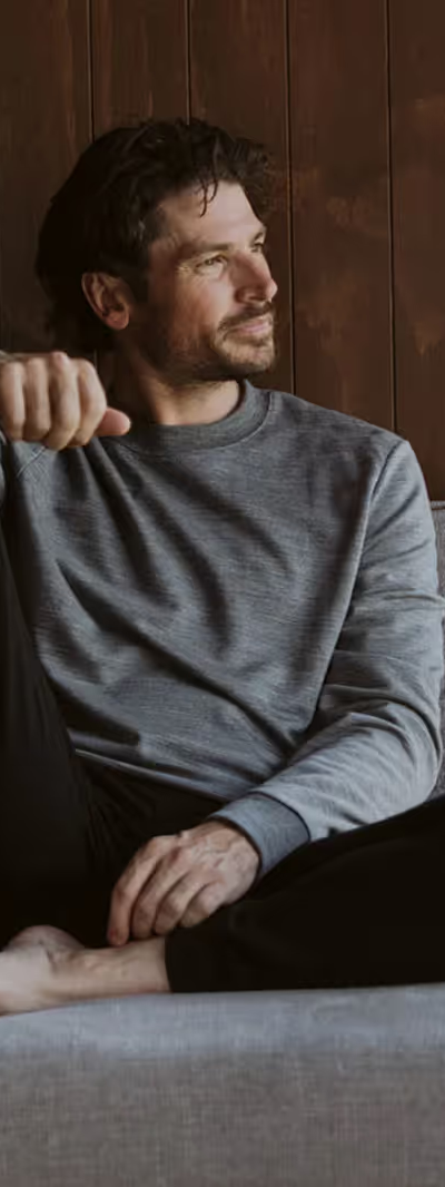 A man sitting in an Icebreaker grey sweatshirt and black pants
