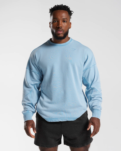 A man wearing a baby blue Gymshark sweatshirt and short black shorts