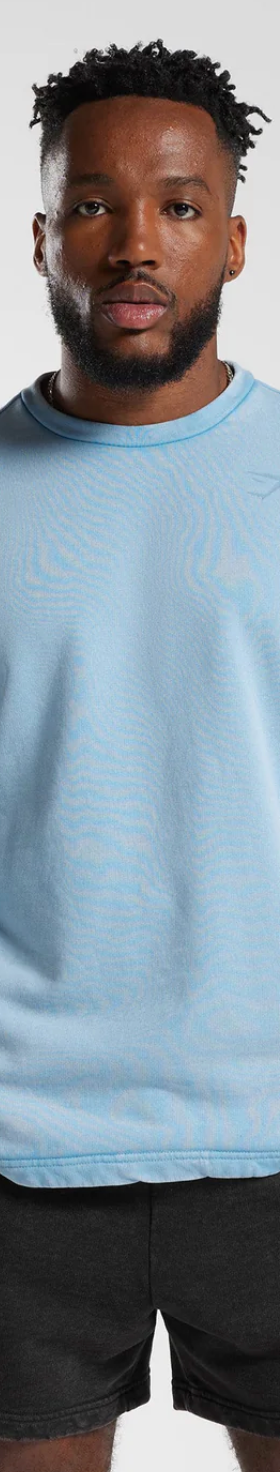 A man wearing a baby blue Gymshark sweatshirt and short black shorts