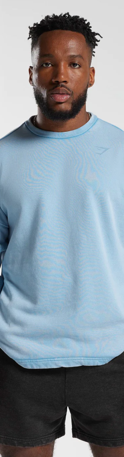 A man wearing a baby blue Gymshark sweatshirt and short black shorts