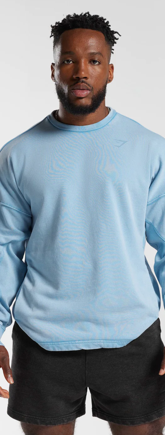 A man wearing a baby blue Gymshark sweatshirt and short black shorts