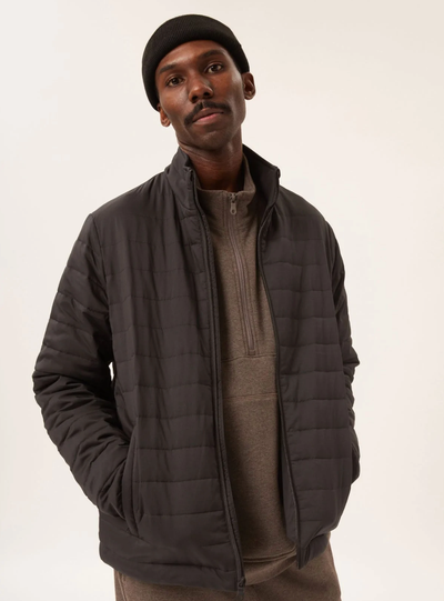 A man wearing a Girlfriend Collective puffy black coat with a black beanie