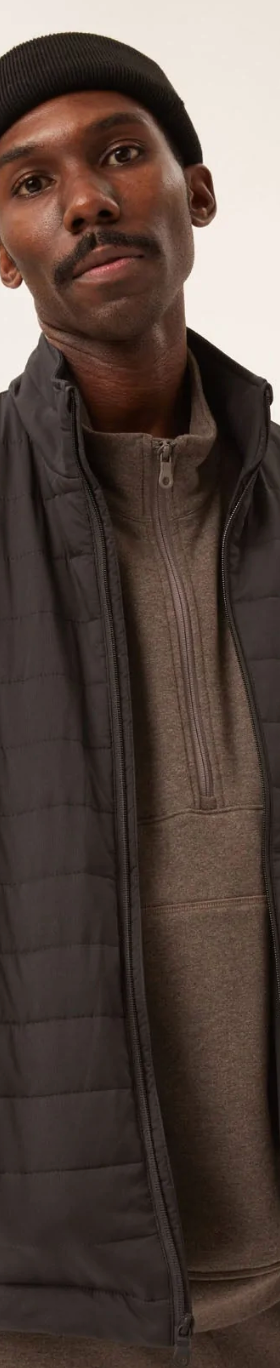 A man wearing a Girlfriend Collective puffy black coat with a black beanie