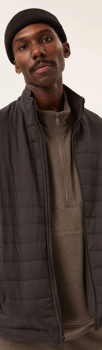 A man wearing a Girlfriend Collective puffy black coat with a black beanie