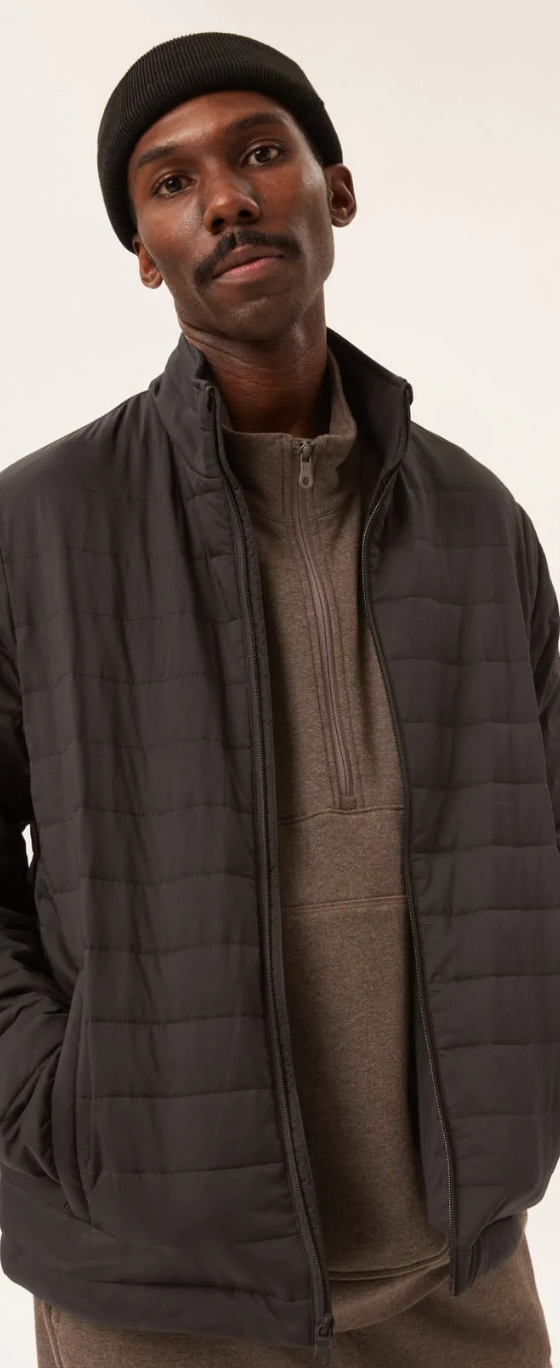A man wearing a Girlfriend Collective puffy black coat with a black beanie