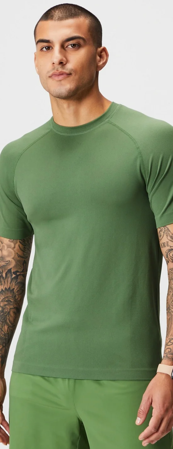 A man wearing a tight-fitting green Fabletics athletic shirt and pants