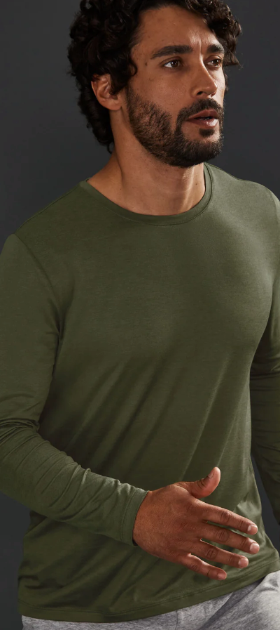 A man wearing a tight-fitting green Beyond Yoga athletic long-sleeve