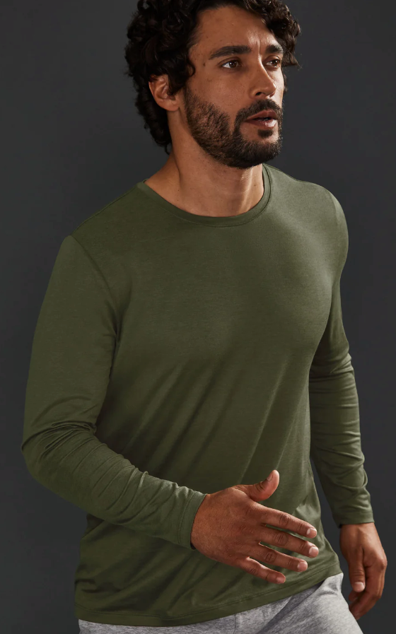 A man wearing a tight-fitting green Beyond Yoga athletic long-sleeve
