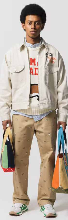 A man wearing a layered Human Made outfit featuring a cream jacket and brown patterned pants