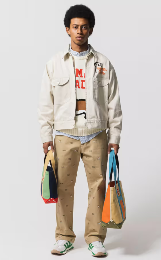 A man wearing a layered Human Made outfit featuring a cream jacket and brown patterned pants