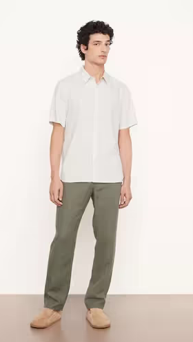 A man wearing a Vince outfit featuring a white short-sleeve button-up and green pants