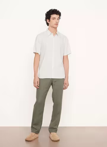 A man wearing a Vince outfit featuring a white short-sleeve button-up and green pants