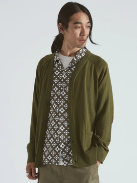 A man wearing a Universal Works green cardigan with a green patterned button up underneath