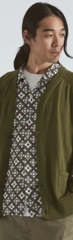 A man wearing a Universal Works green cardigan with a green patterned button up underneath