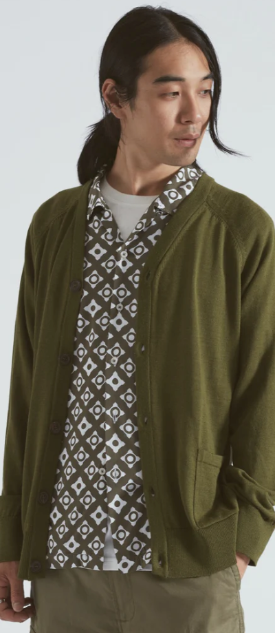 A man wearing a Universal Works green cardigan with a green patterned button up underneath