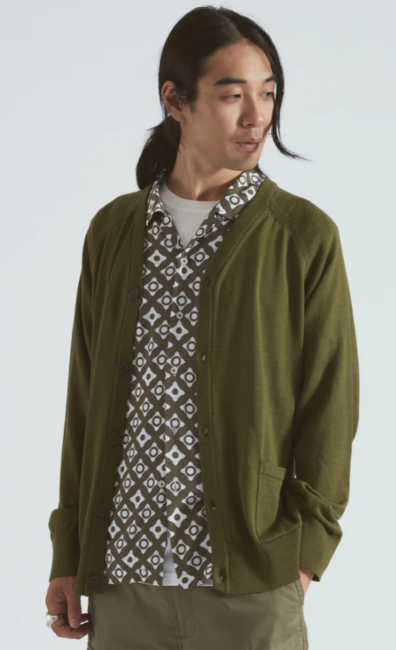 A man wearing a Universal Works green cardigan with a green patterned button up underneath