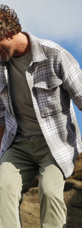 A man climbing outdoors wearing a Outerknown plaid overshirt with light green pants