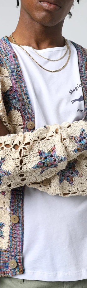 A man wearing a Corridor knitted and colorful cardigan with a white t-shirt underneath
