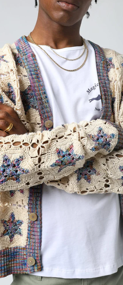 A man wearing a Corridor knitted and colorful cardigan with a white t-shirt underneath