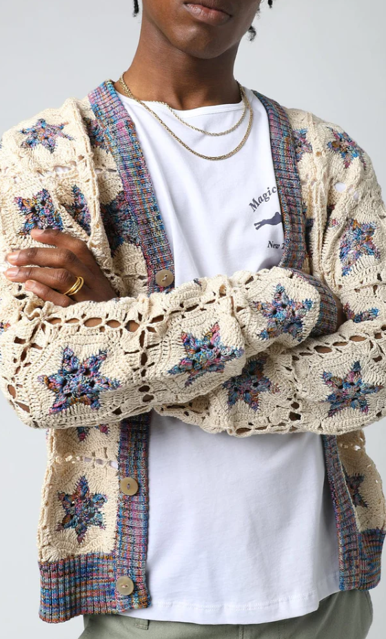 A man wearing a Corridor knitted and colorful cardigan with a white t-shirt underneath