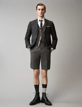 A man wearing a Thom Browne short suit with high socks and dress shoes