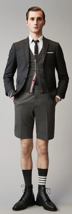 A man wearing a Thom Browne short suit with high socks and dress shoes