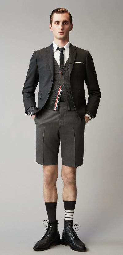 A man wearing a Thom Browne short suit with high socks and dress shoes
