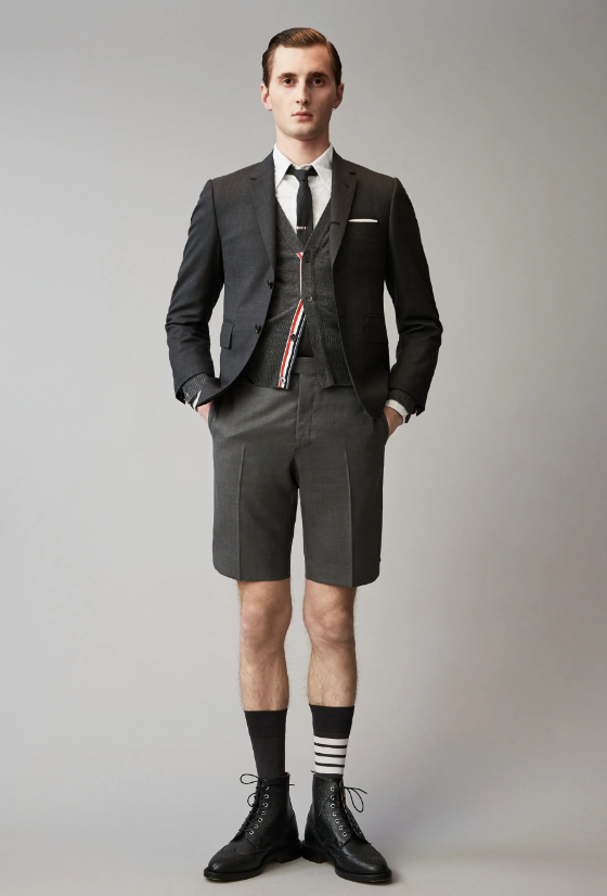 A man wearing a Thom Browne short suit with high socks and dress shoes
