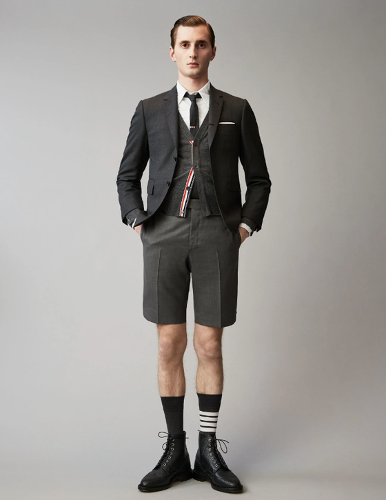 A man wearing a Thom Browne short suit with high socks and dress shoes