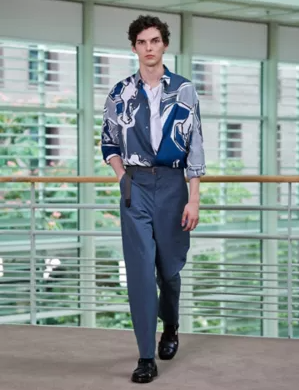A man wearing a blue Hermes button up with blue pants