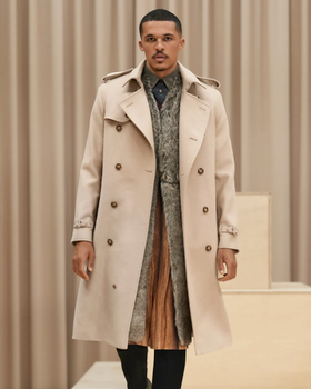 A man wearing a light brown Burberry trench coat with a large floral jacket underneath