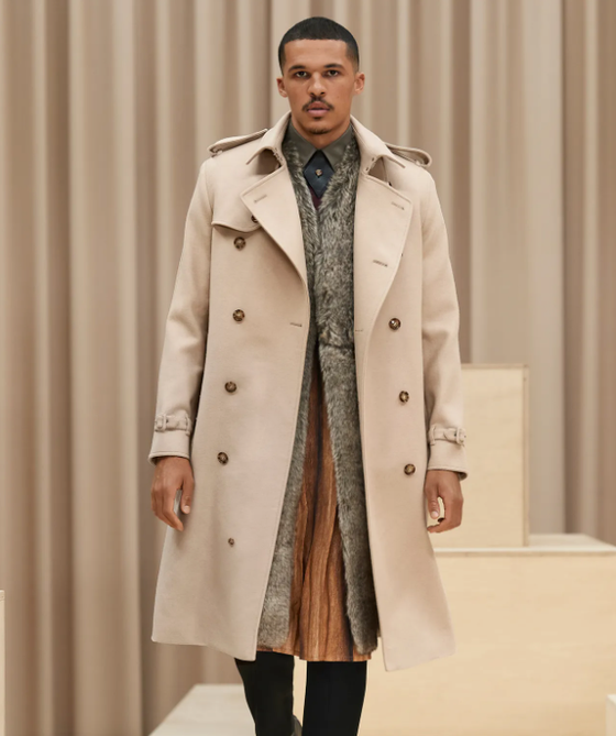A man wearing a light brown Burberry trench coat with a large floral jacket underneath