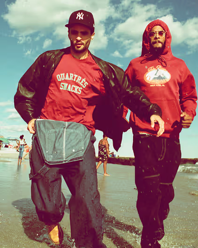 Two men walking on the beach wearing red QuarterSnacks Sweatshirts and baggy pants