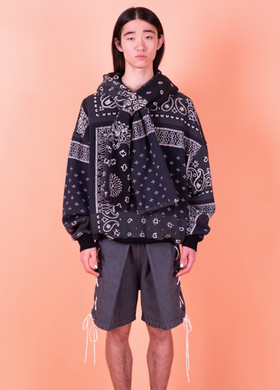 A man wearing a Kapital jacket with a black bandana print and shorts