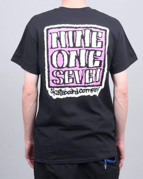 A man wearing a Call Me 917 t-shirt with a large print on the back in pink and white