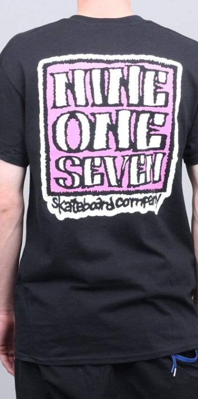 A man wearing a Call Me 917 t-shirt with a large print on the back in pink and white