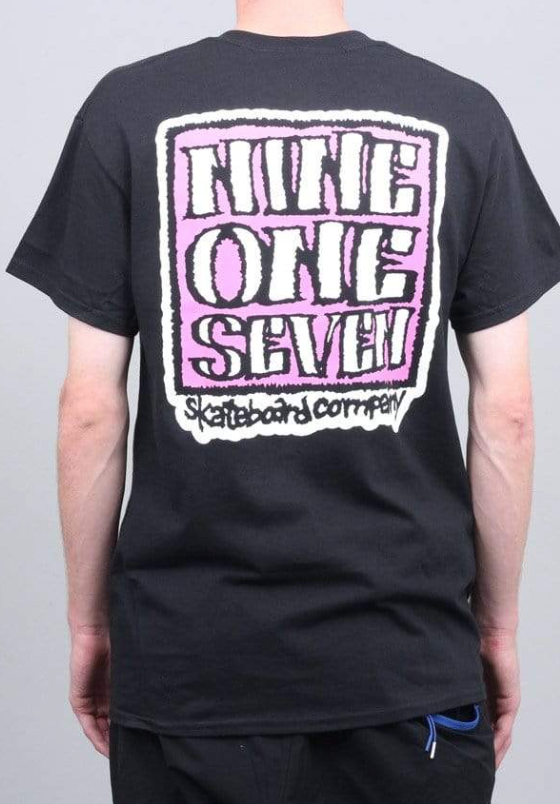A man wearing a Call Me 917 t-shirt with a large print on the back in pink and white