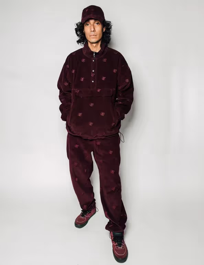 A man wearing a Bronze 56k black fleece with matching pants and red nikes