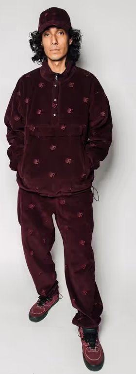 A man wearing a Bronze 56k black  fleece with matching pants and red nikes