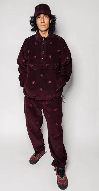 A man wearing a Bronze 56k black  fleece with matching pants and red nikes