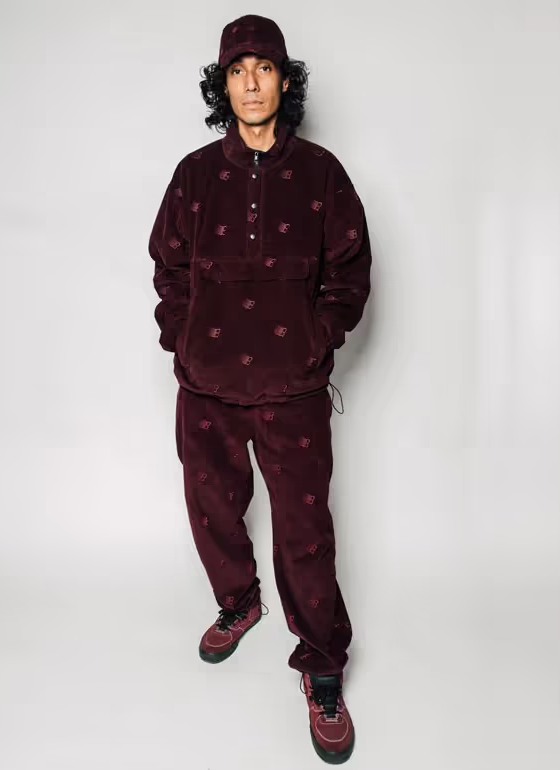A man wearing a Bronze 56k black  fleece with matching pants and red nikes