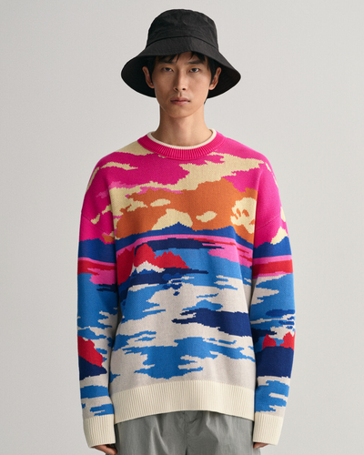 A man wearing a Gant sunset sweater, grey pants and a black bucket hat