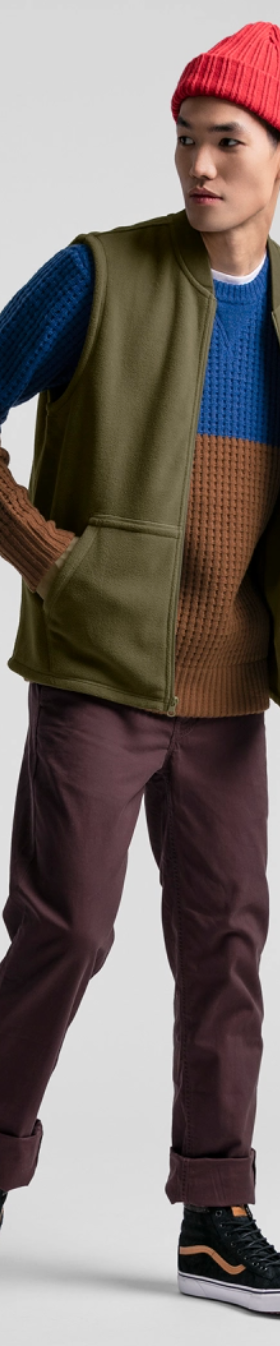 A man wearing a JackThreads outfit featuring a red beanie. green vest and red pants