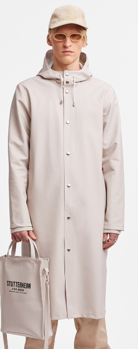 A man wearing a contemporary beige Stutterheim raincoat with matching hat and sunglasses